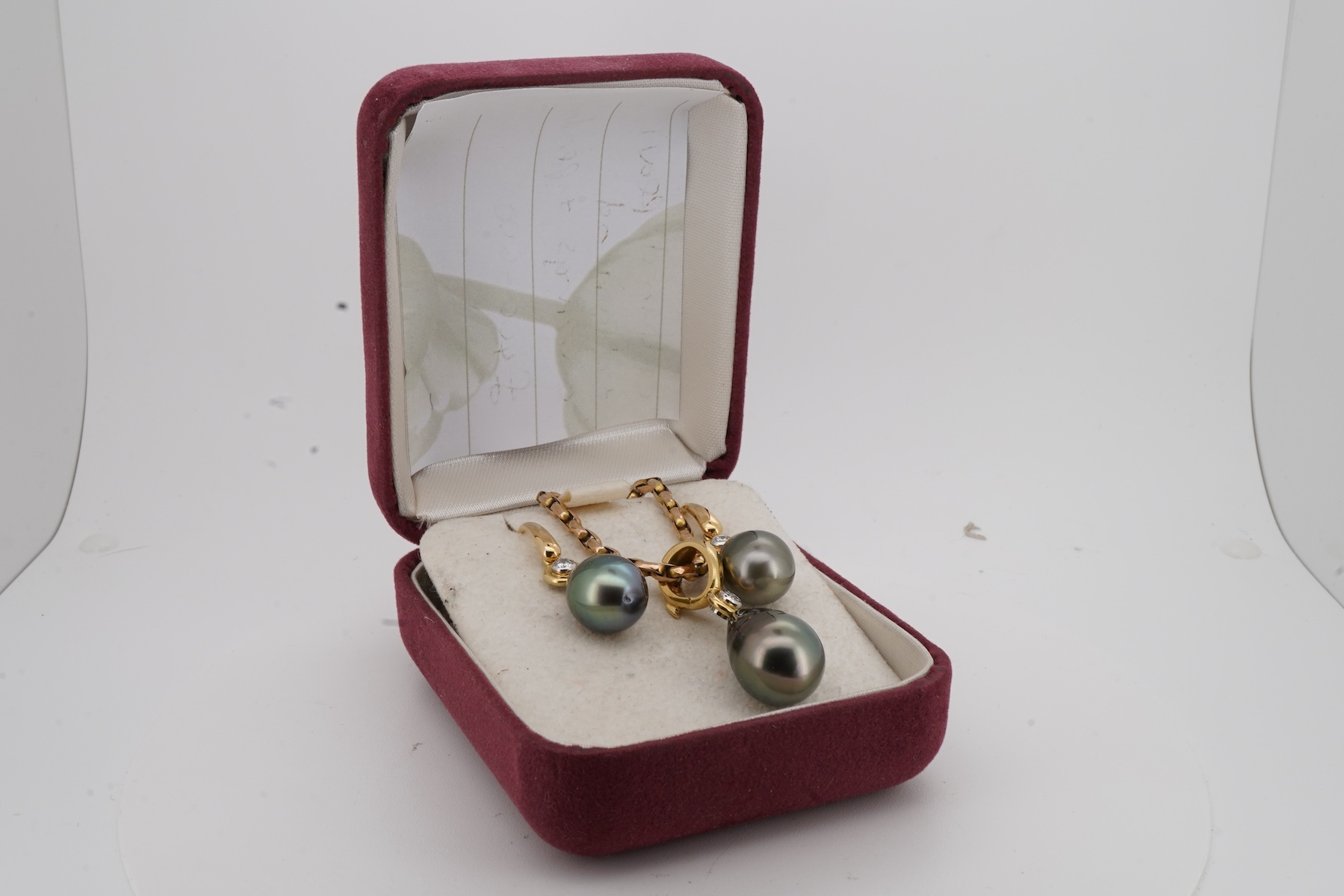 A cultured pearl and diamond demi-parure, comprising: a pendant, suspending a drop-shaped cultured pearl of black tint, measuring approximately 15 x 10.5 x 10.5mm, surmounted by a collet-set brilliant-cut diamond weighin